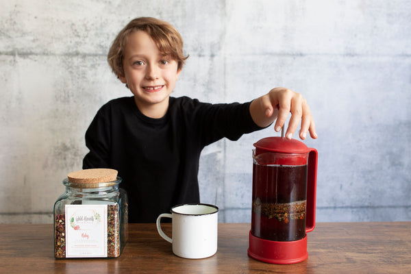 Young kid pressing Ruby Nourishing Tea Blend. Herbal teas for kids. Healthy juice alternative. Herbalist formulated.